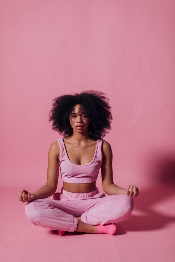 A woman meditating on a pink background
