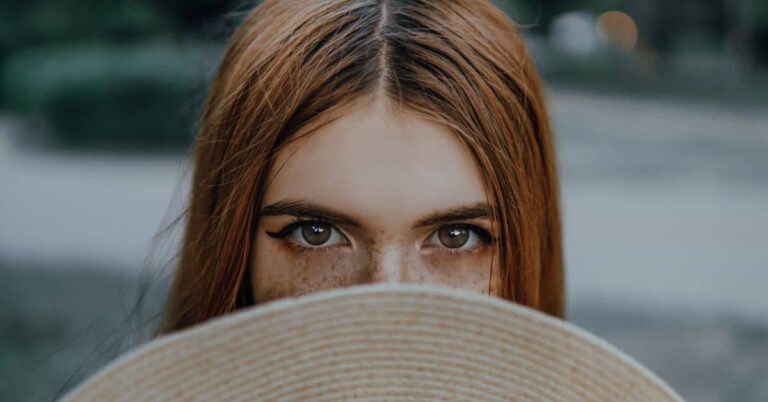 Brown eyes symbolism - A person with brown eyes peeking from behind a hat