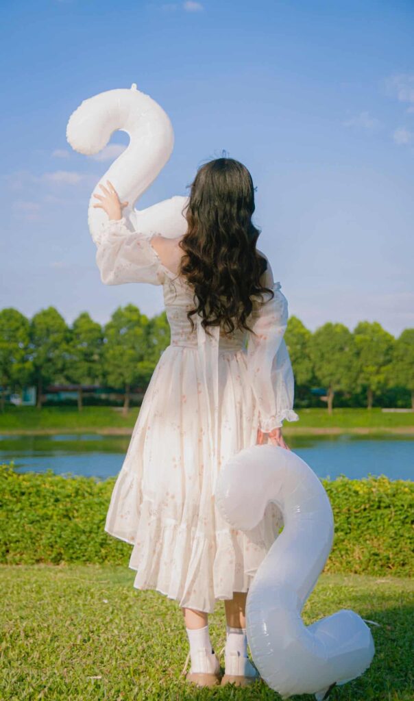 A woman with her back to the camera holding two white number two shaped balloons