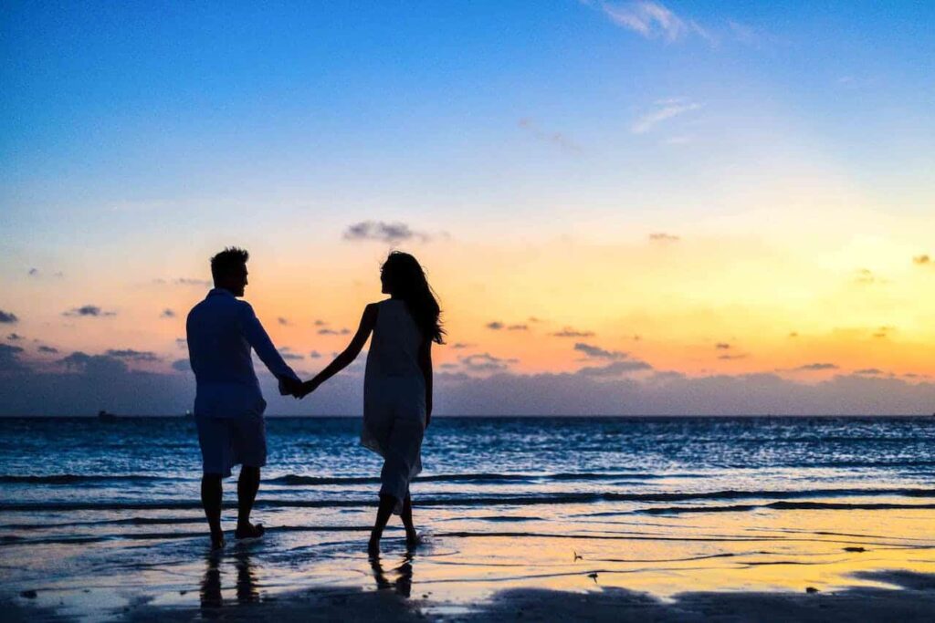 Couple holding hands on a  beach by sunset