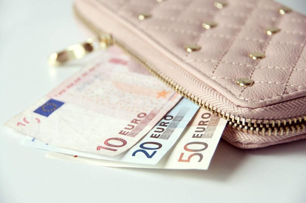 Euro notes peeking out of a pink wallet