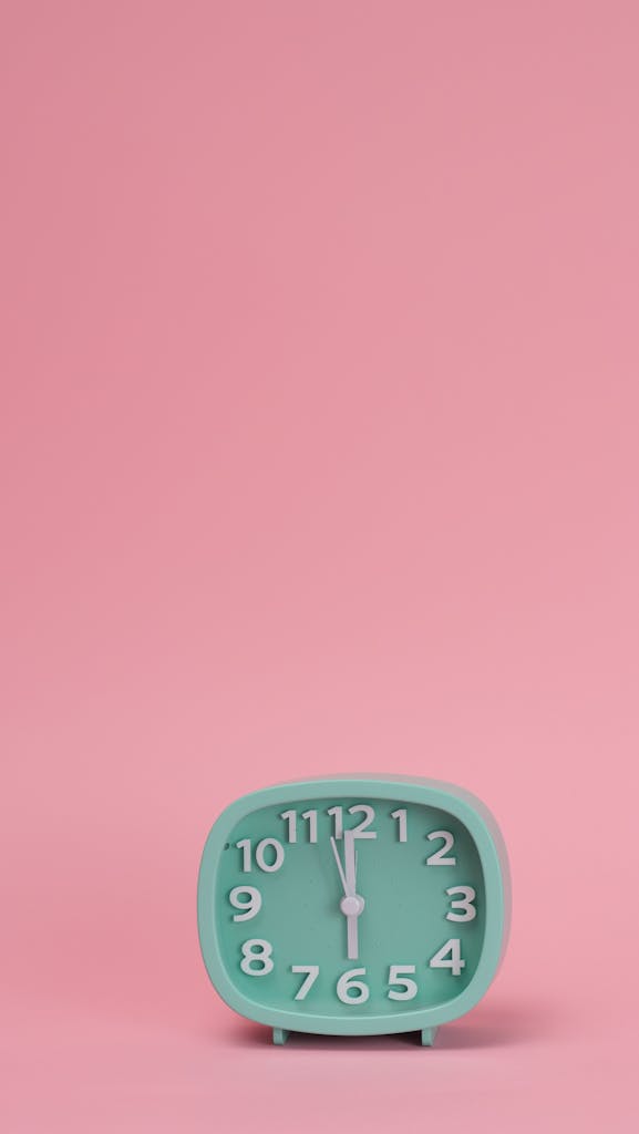 A Green Analog Clock on Pink Background